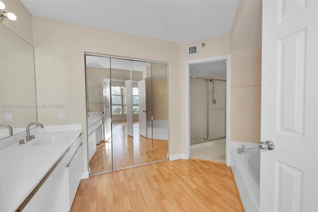 bathroom featuring independent shower and bath, a textured ceiling, vanity, and hardwood / wood-style floors