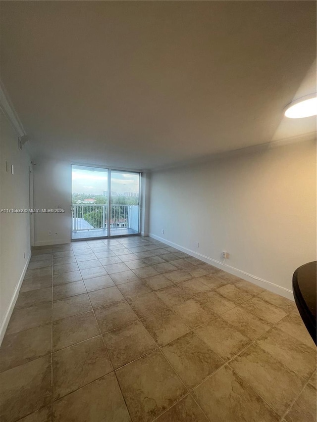 tiled empty room featuring a wall of windows and ornamental molding