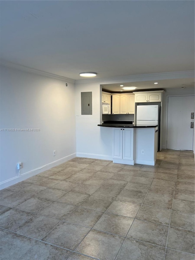 kitchen featuring crown molding, dark countertops, white appliances, a peninsula, and electric panel