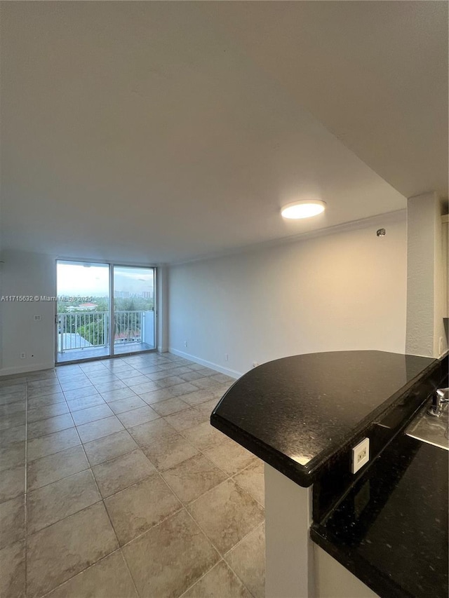 kitchen featuring dark countertops, baseboards, a peninsula, and open floor plan