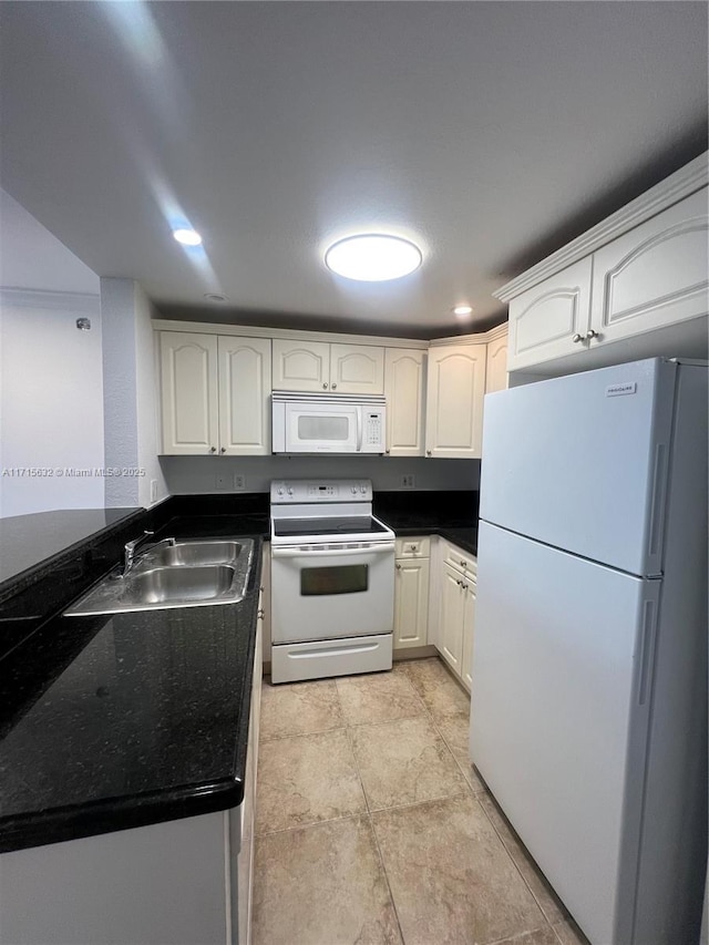 kitchen featuring white appliances, white cabinetry, dark countertops, and a sink