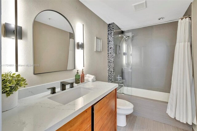 full bathroom with tiled shower / bath, vanity, and toilet