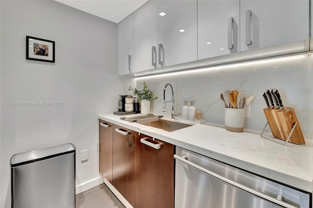 kitchen with sink, light stone counters, dishwasher, white cabinets, and backsplash