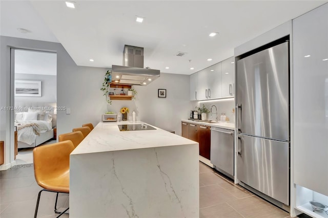 kitchen with a kitchen bar, sink, white cabinetry, light stone counters, and appliances with stainless steel finishes