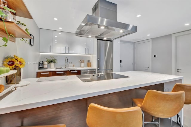 kitchen featuring appliances with stainless steel finishes, a breakfast bar area, island range hood, and sink