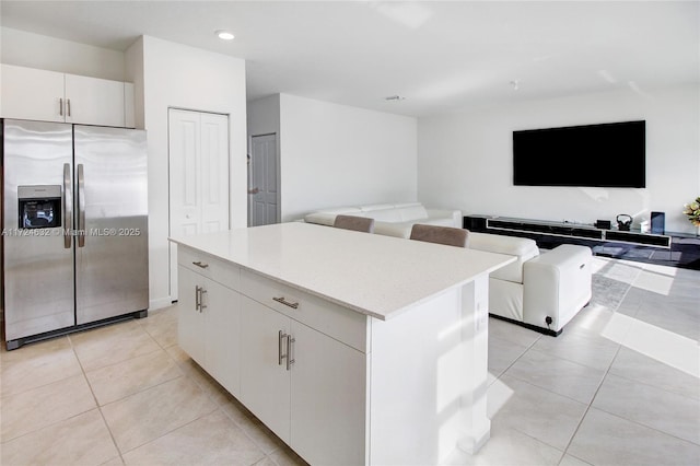 kitchen featuring white cabinets, a center island, stainless steel fridge with ice dispenser, and light tile patterned floors