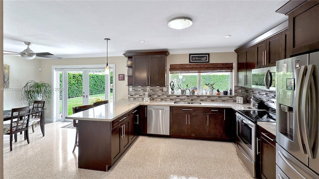 kitchen featuring sink, hanging light fixtures, stainless steel appliances, tasteful backsplash, and kitchen peninsula