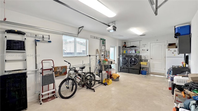 garage with washing machine and clothes dryer, white fridge, and a garage door opener