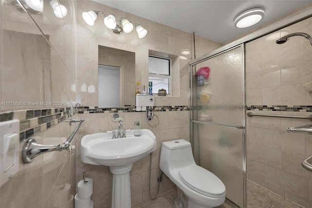 bathroom featuring toilet, tile walls, a shower with shower door, and sink