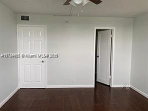 unfurnished room with ceiling fan and dark wood-type flooring