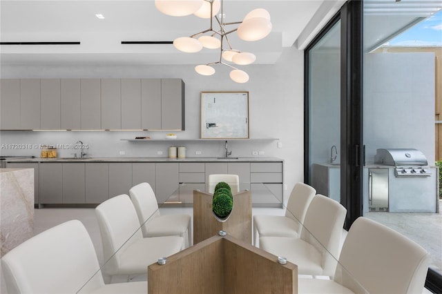 kitchen featuring a chandelier, pendant lighting, gray cabinets, and sink