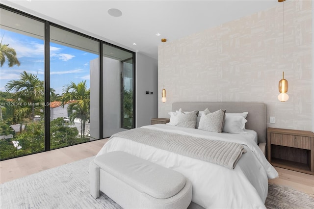 bedroom featuring access to exterior, wood-type flooring, and a wall of windows