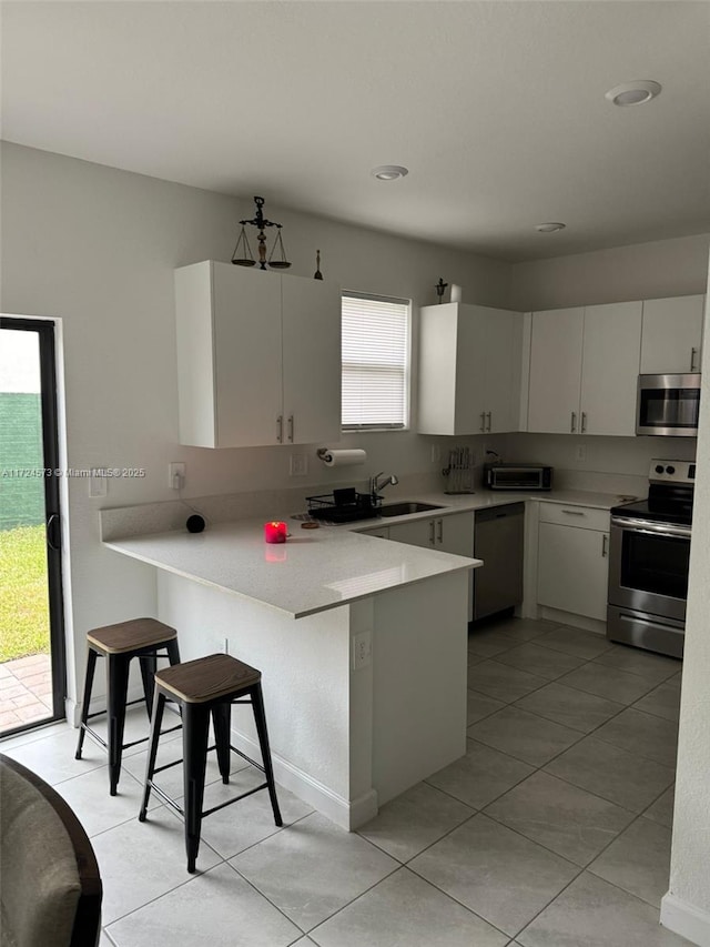 kitchen featuring kitchen peninsula, stainless steel appliances, and white cabinetry