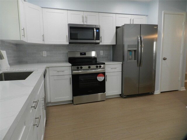 kitchen featuring stainless steel appliances, white cabinetry, sink, and tasteful backsplash