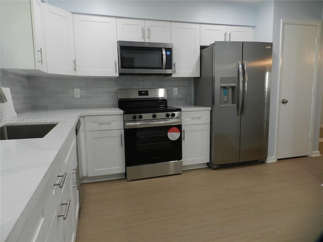 kitchen featuring sink, stainless steel appliances, light stone countertops, decorative backsplash, and white cabinets