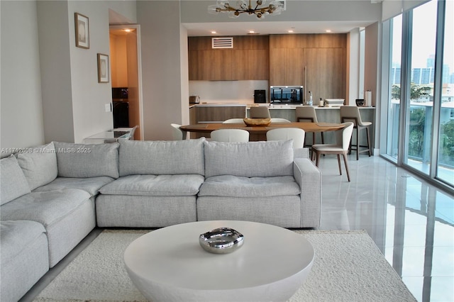 living room featuring expansive windows, a notable chandelier, and wooden walls