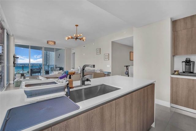 kitchen with floor to ceiling windows, a notable chandelier, pendant lighting, a water view, and sink