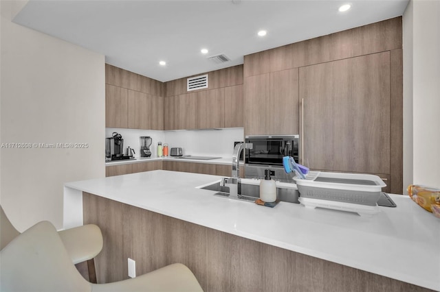 kitchen with a kitchen bar, black appliances, and kitchen peninsula