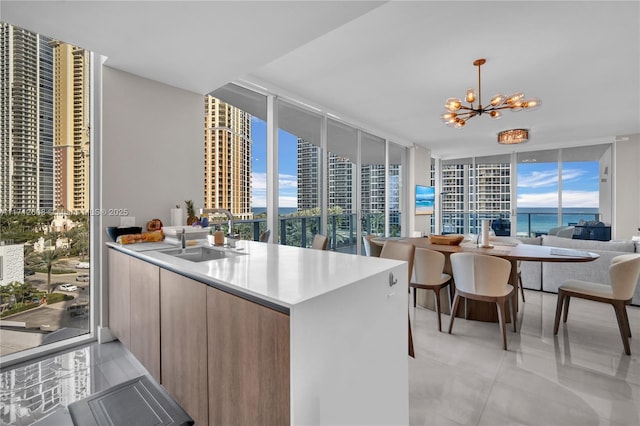 kitchen featuring floor to ceiling windows, kitchen peninsula, sink, hanging light fixtures, and a chandelier