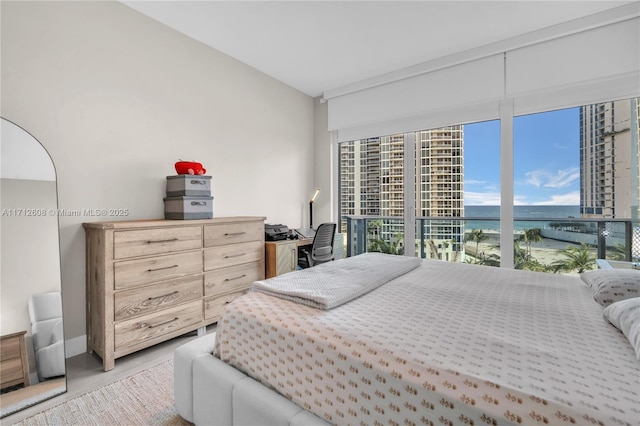 bedroom with light wood-type flooring, a water view, and access to outside