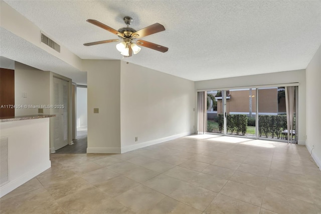 empty room with light tile patterned floors, a textured ceiling, and ceiling fan