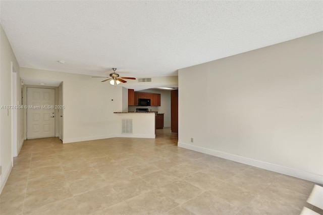 unfurnished living room featuring ceiling fan and a textured ceiling