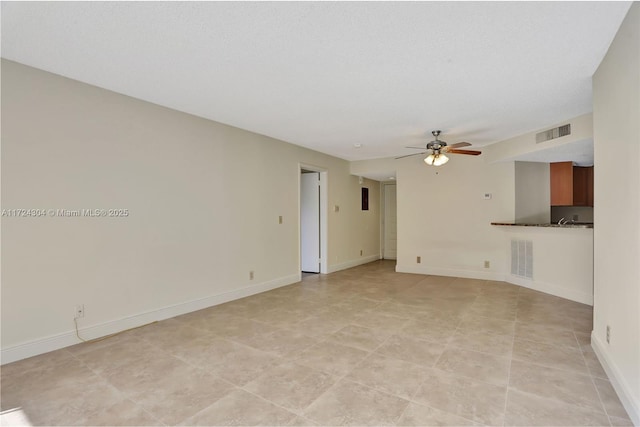 unfurnished living room featuring ceiling fan and a textured ceiling