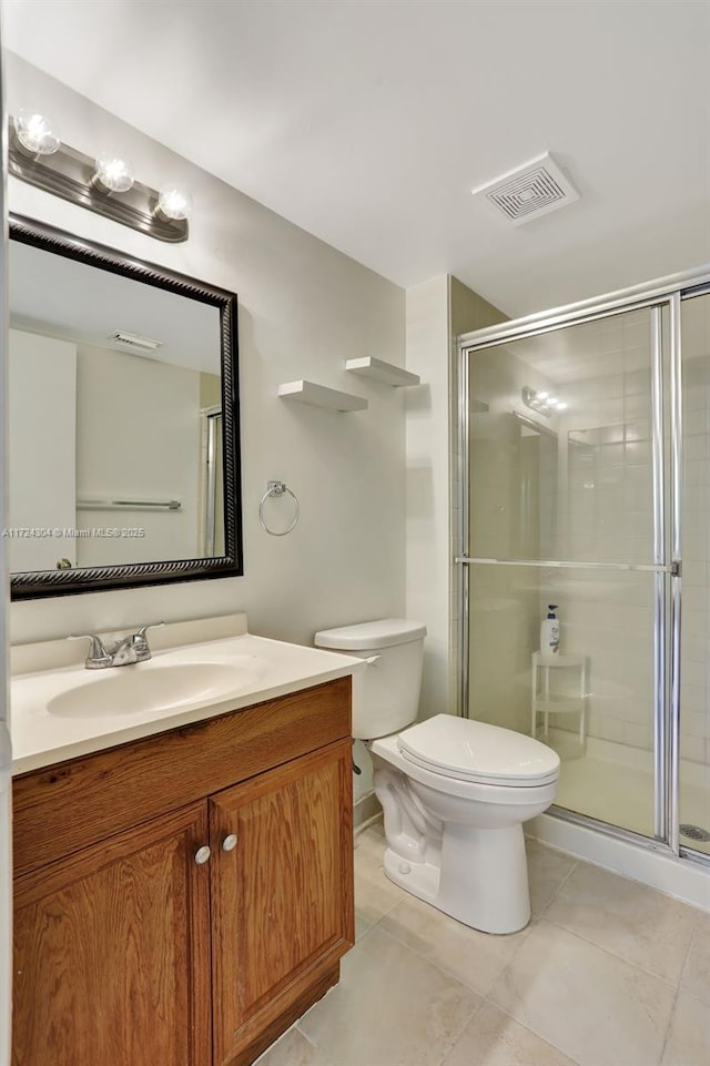 bathroom featuring tile patterned floors, vanity, a shower with shower door, and toilet