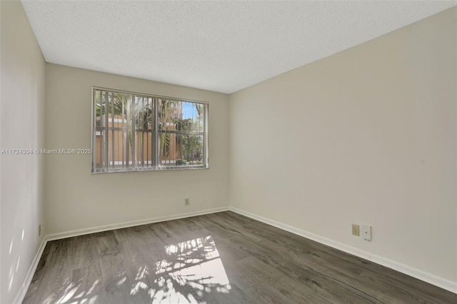 empty room with dark wood-type flooring and a textured ceiling