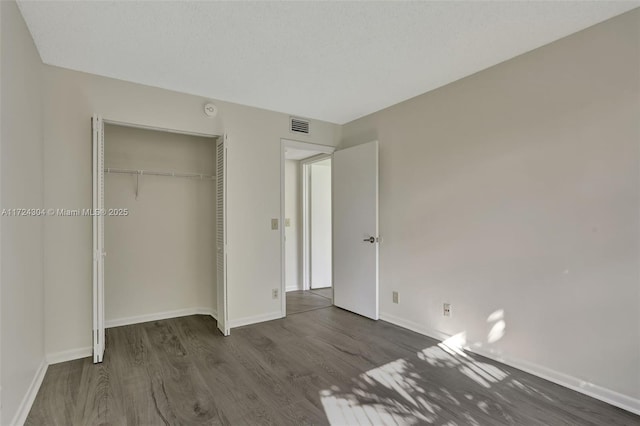 unfurnished bedroom featuring dark hardwood / wood-style floors and a closet