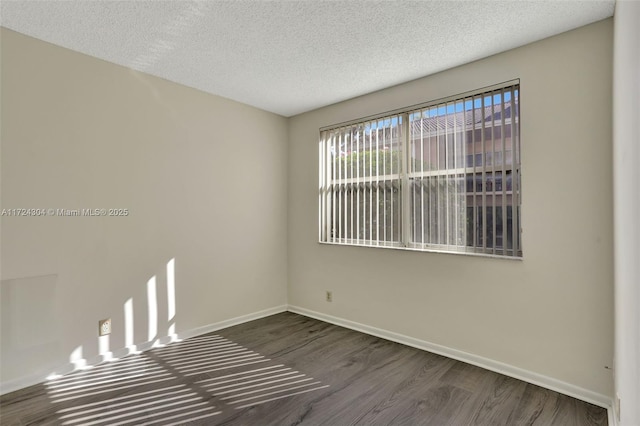 empty room with a textured ceiling and dark hardwood / wood-style floors