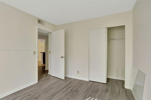 unfurnished bedroom featuring a closet, light hardwood / wood-style flooring, and a textured ceiling