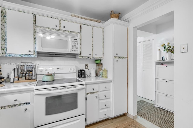 kitchen featuring backsplash, light hardwood / wood-style flooring, white cabinets, and white appliances