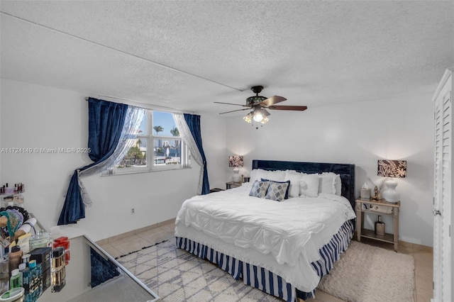 tiled bedroom with ceiling fan and a textured ceiling