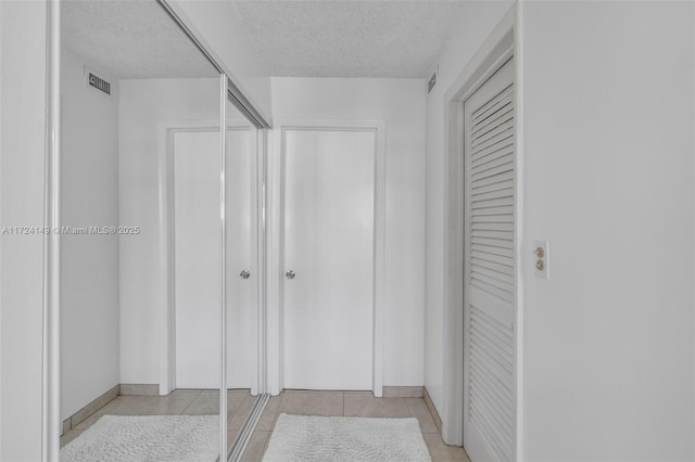 interior space with light tile patterned flooring, a textured ceiling, and a closet