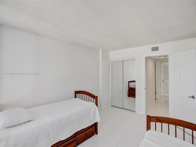 tiled bedroom featuring a closet and a textured ceiling