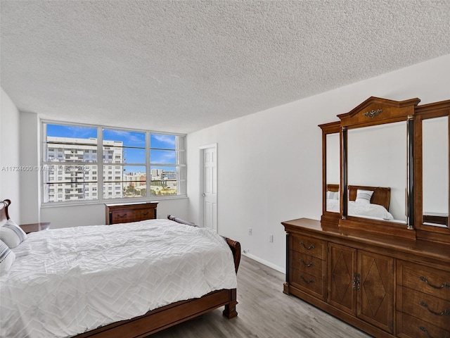 bedroom with a textured ceiling and light hardwood / wood-style flooring