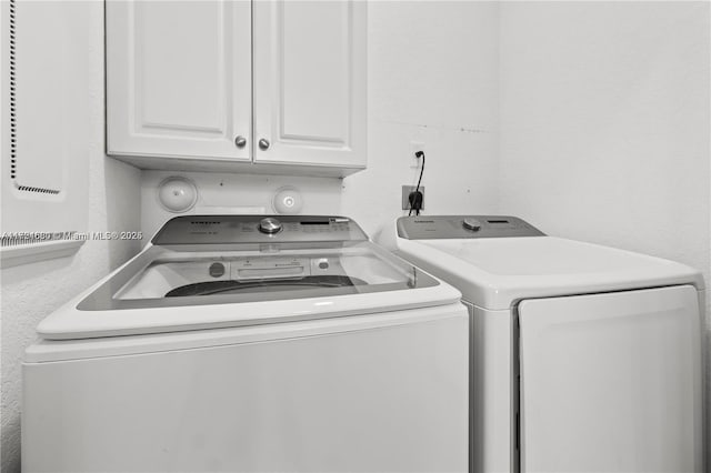 washroom with washer and dryer and cabinets