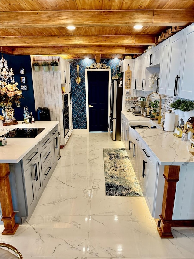 kitchen with wooden ceiling, light stone countertops, beamed ceiling, stainless steel fridge, and sink