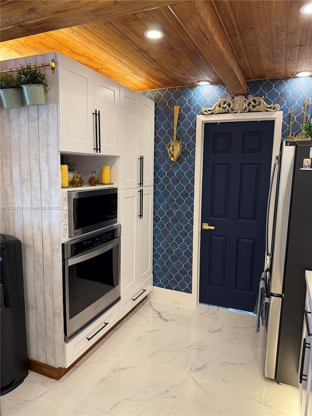 kitchen featuring stainless steel appliances, beam ceiling, white cabinets, and wooden ceiling