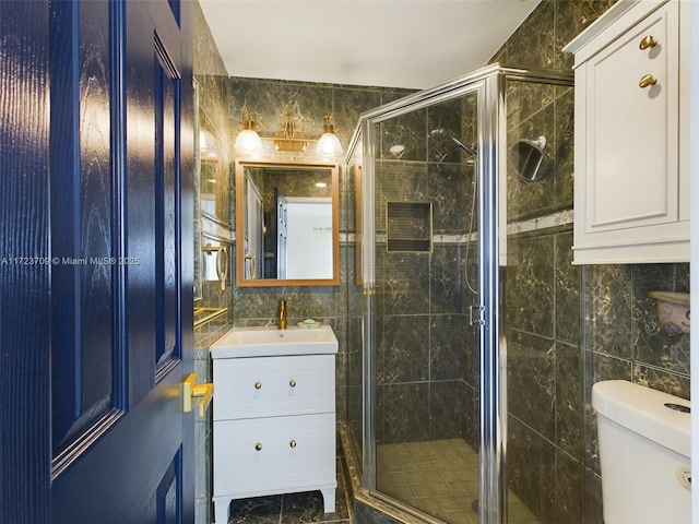 bathroom with toilet, a shower with door, vanity, and tile walls