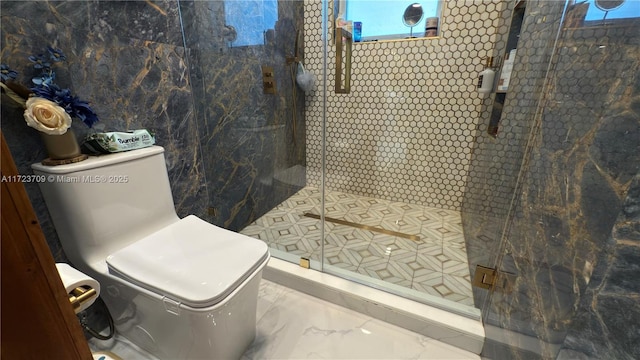 bathroom featuring a shower with shower door and toilet