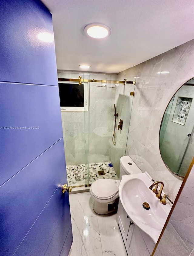 bathroom with tile walls, a shower with shower door, vanity, and toilet