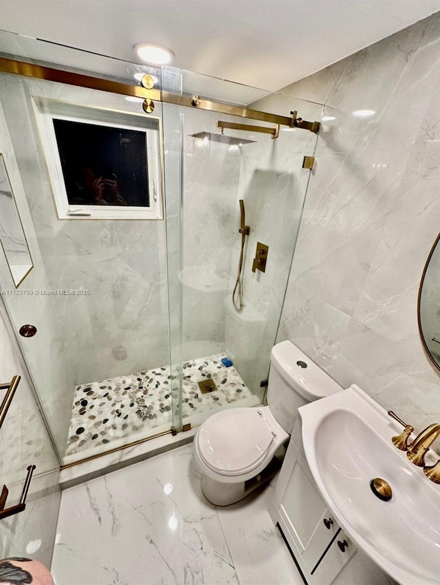 bathroom with sink, a shower with door, tile walls, and toilet