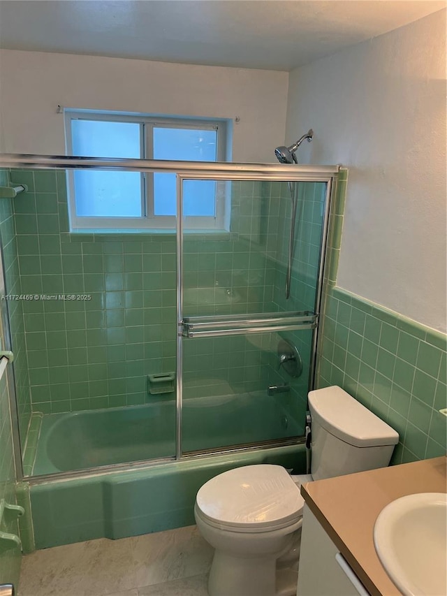 full bathroom featuring vanity, combined bath / shower with glass door, tile patterned flooring, toilet, and tile walls