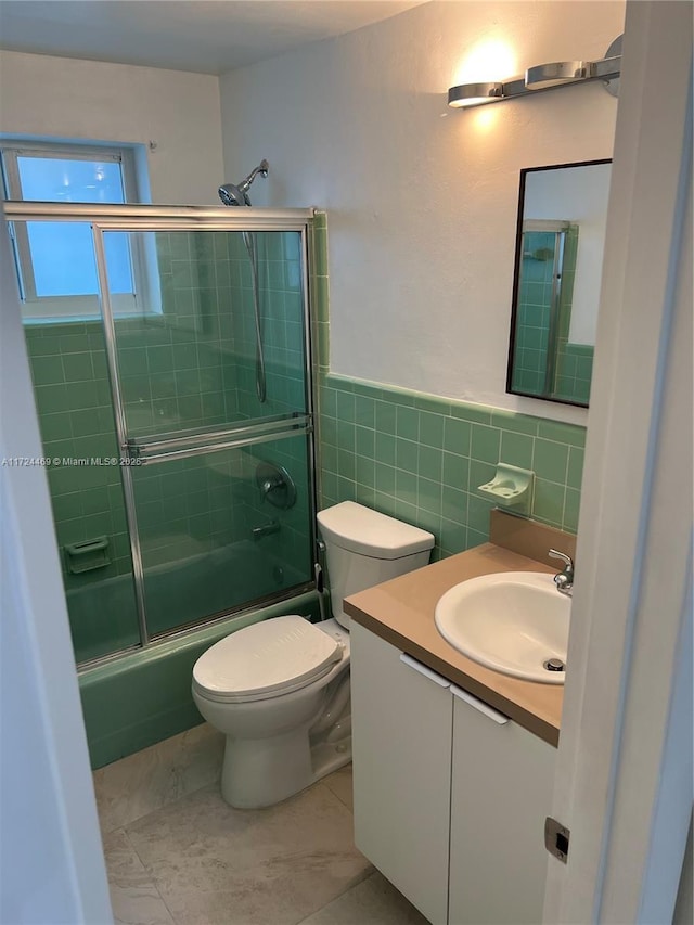 full bathroom featuring vanity, tile walls, enclosed tub / shower combo, tile patterned flooring, and toilet