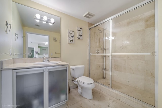 bathroom featuring toilet, vanity, and a shower with shower door