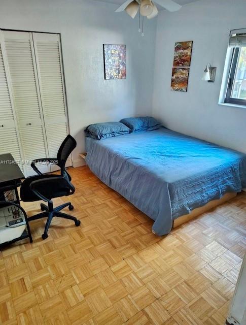 bedroom featuring ceiling fan, light parquet flooring, and a closet