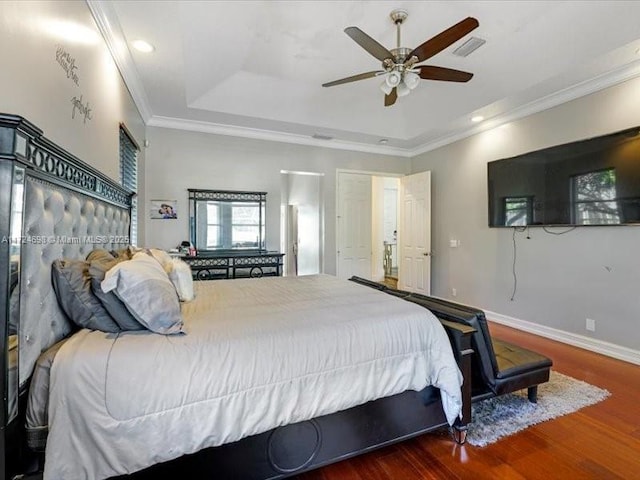 bedroom featuring ceiling fan, crown molding, dark hardwood / wood-style floors, and a tray ceiling