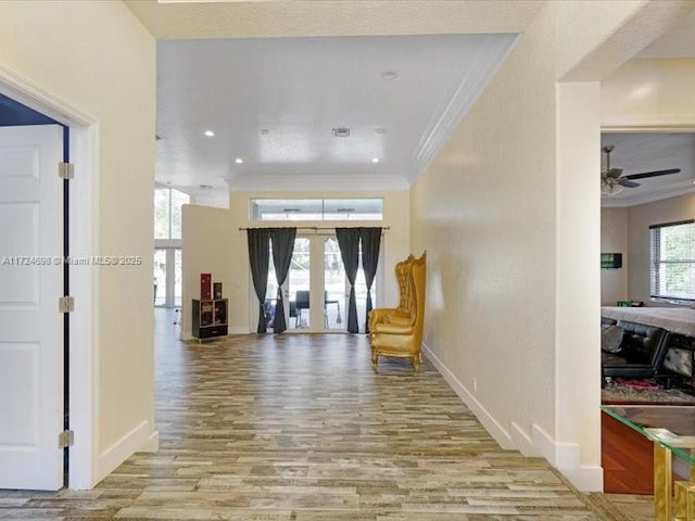 corridor featuring light wood-type flooring, ornamental molding, and french doors